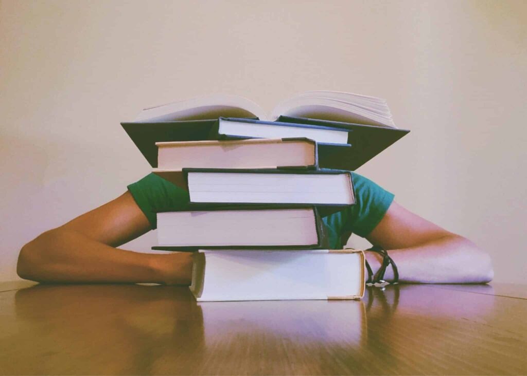 Student zit weggedoken achter een stappel boeken